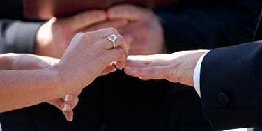 couple putting ring on finger in marriage ceremony