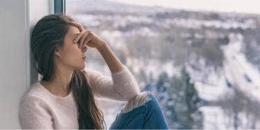 sad woman sitting by window in winter