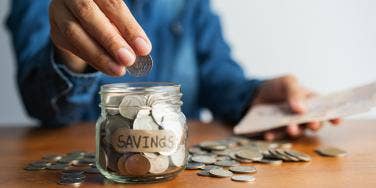 man putting coins in jar