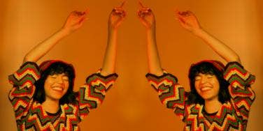 woman with her arms up in the air on orange background