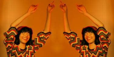 woman with her arms up in the air on orange background