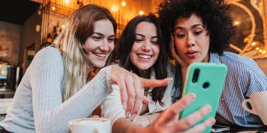 Group of young women having fun sharing media with an cellphone.