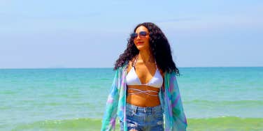 joyful woman in shorts and bikini top in front of a Caribbean beach