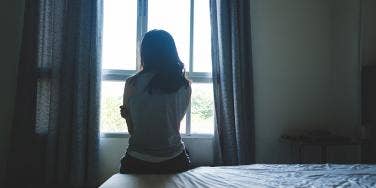 woman in shadow looking out window