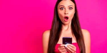 woman looking shocked after checking her phone