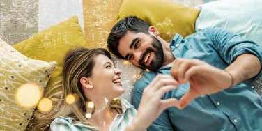 couple laying on floor making a heart with their hands