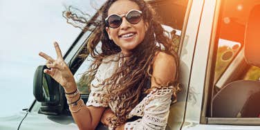 Woman peace sign hanging out car window