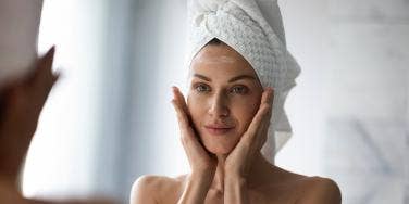 woman looking in mirror with towel on her head