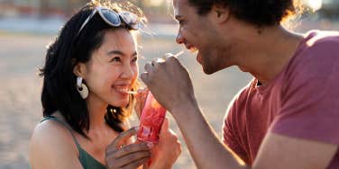 man smiling at woman while sharing a juicebox