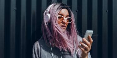 woman with purple hair listening to music on her phone