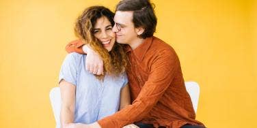 couple cuddling in front of yellow background