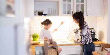 mom and toddler daughter cooking together in the kitchen