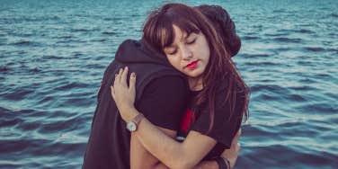 woman hugging man over the water