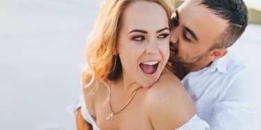 young guy kisses a beautiful fun woman on the beach