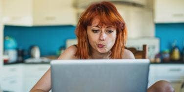 woman with red hair looking at computer screen