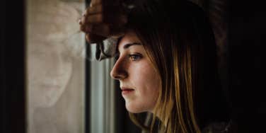 Hurt woman looking out window 