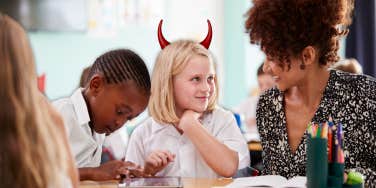 smiling girl with devil horns in class