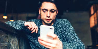 man looking at phone hoping his text messages will save his relationship