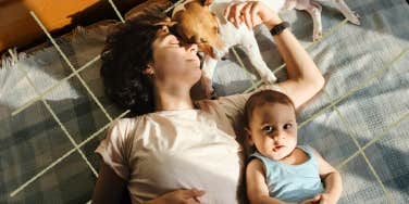 mom laying dow with her baby and dog