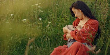 mother holding baby in field breastfeeding