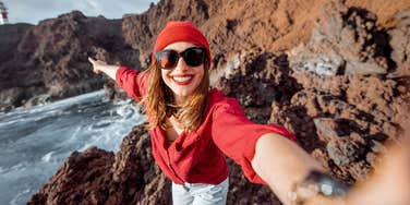woman takes a selfie on a cliff near the ocean