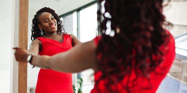 confident woman in red dress looking in mirror