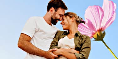 couple in front of a blue sky and big pink flower 