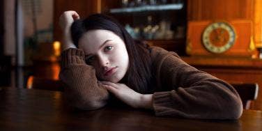 glum-looking woman with her head on the table