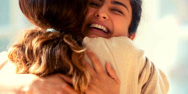 woman smiling while hugging her friend
