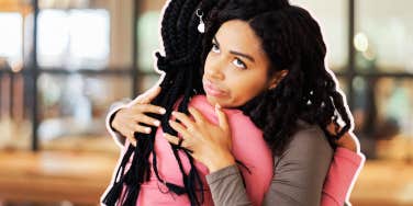 Two women hugging, rolling eyes behind her back