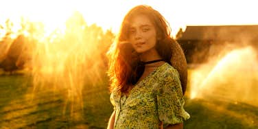 Woman in ethereal setting looks at camera with small smile.