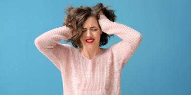 frustrated woman in pink sweater and blue background