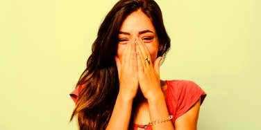 embarrassed woman laughing covering mouth