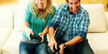 man woman playing video games on sofa