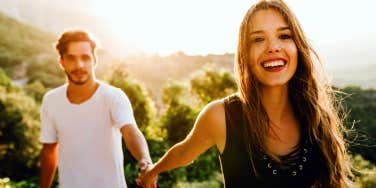 young woman holds hands with a man while hiking