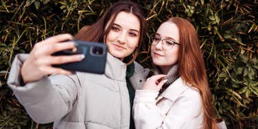 two young girls taking selfie with phone