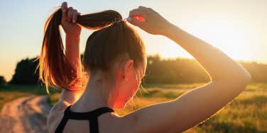 woman putting hair in ponytail