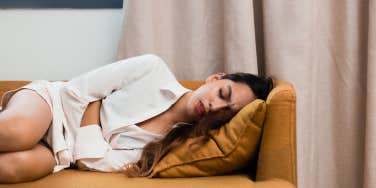 woman laying on couch with period cramps