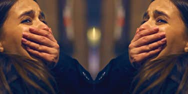 mirror image of woman covering her mouth in shock