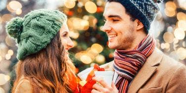 man and woman in winter hats toasting cups