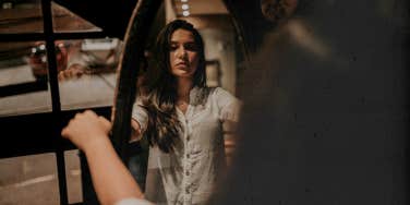 Woman grasping the sides of the mirror, looking at herself