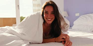 smiling woman in bed under covers