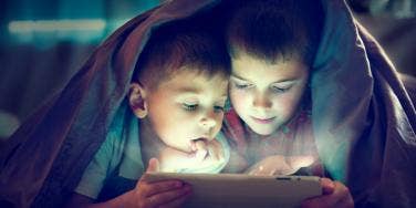 two boys under blanket in dark
