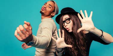 Portrait of a funny young modern couple dancing and having fun together over blue background