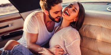 Romantic couple is sitting in green retro car on the beach