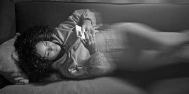 woman laying on couch texting on phone