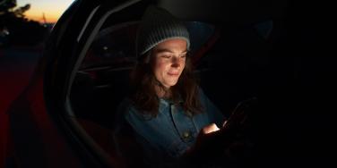 A woman is in the back of a car at night.