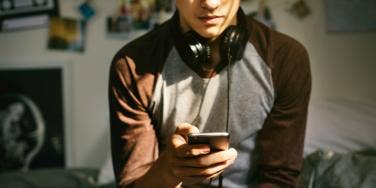 teen boy wearing headphones looks at his phone