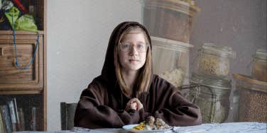 Little kid sitting down at table with food