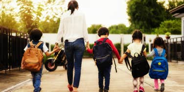 mom holding hands with children walking to school